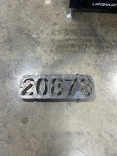 CNC plasma-cut metal plate marked 20878 on a workshop floor