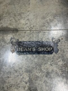 Custom metal “Dean’s Shop” sign featuring deer silhouettes and a textured gray finish