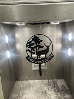 Powder-coated deer emblem inside a spray booth, showcasing custom metal finishing by Darin's Unique Designs.